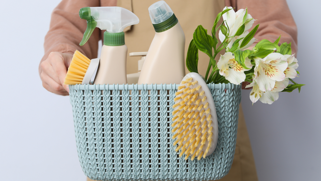 Person die einen Korb mit Reinigungsmitteln und Reinigungsutensilien beinhaltet
