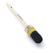 The Nölle Profi Brush Craftsman Ring Brush features a wooden handle with black lettering, emphasizing craftsman quality. It has a metal ferrule and a yellow band with pure black Chinese bristles.