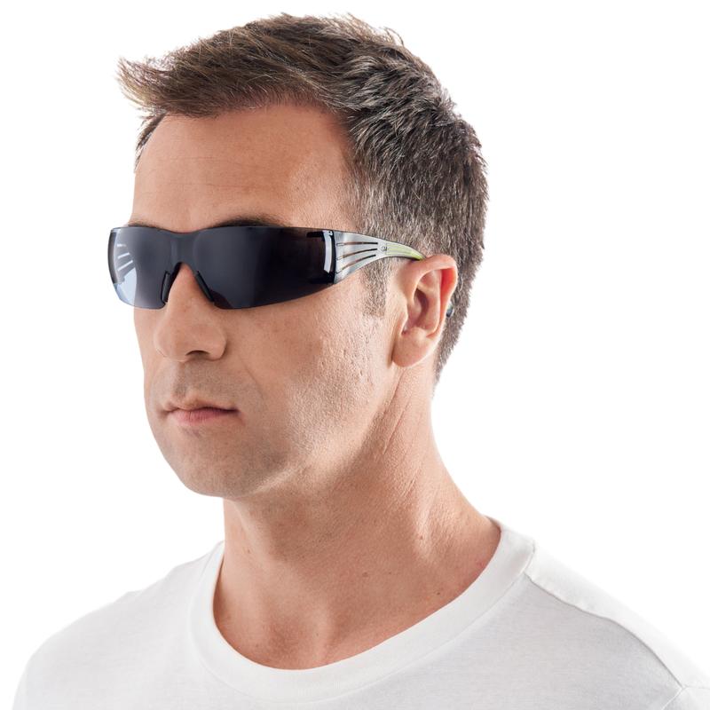 A man with short brown hair models the 3M™ SecureFit™ Safety Glasses 400 from 3M Deutschland GmbH. He wears a black wraparound safety glasses and a white T-shirt against a plain white background.