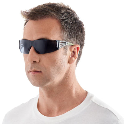 A man with short brown hair models the 3M™ SecureFit™ Safety Glasses 400 from 3M Deutschland GmbH. He wears a black wraparound safety glasses and a white T-shirt against a plain white background.