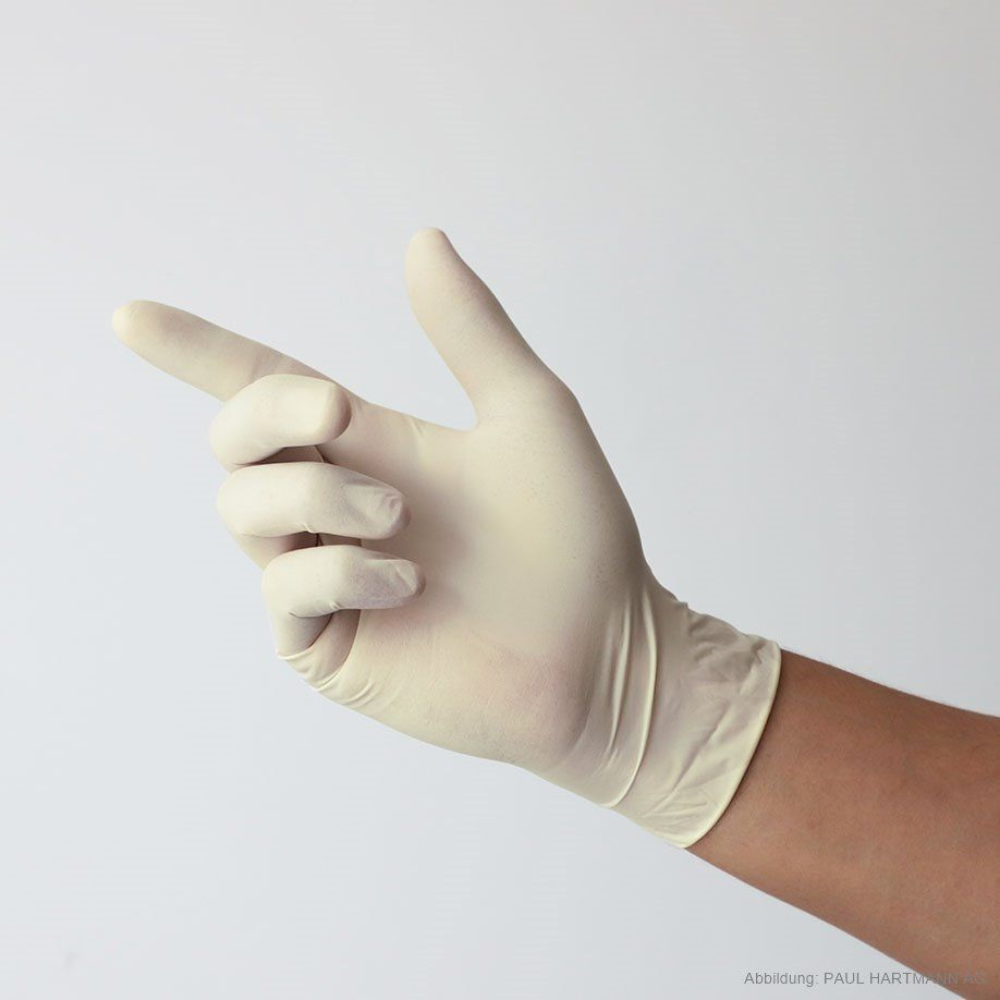 The hand of a person wearing Hartmann Peha-soft Latex Comfort disposable examination gloves by Paul Hartmann AG is seen against a light background with an extended index finger and curved other fingers, emphasizing protection and comfort.