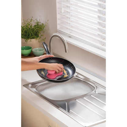 Eine Person reinigt eine Bratpfanne unter fließendem Wasser in einer modernen Küche mit einem 3M Deutschland GmbH Scotch-Brite® Delicate Color Comfort nicht kratzender Reinigungsschwamm (2 Stück)-ideal für empfindliche Oberflächen. Grüne Schalen und eine Pflanze stehen auf der Arbeitsplatte.