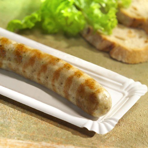 A grilled sausage on a PAPSTAR 250 plate, cardboard "pure" square white by PAPSTAR GmbH, served with salad leaves and two slices of bread in the background.