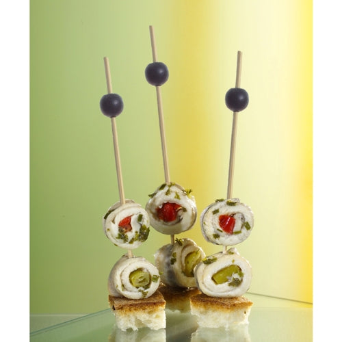 Three PAPSTAR 250 finger food picks from PAPSTAR GmbH hold cheese, herb, and vegetable rolls on bread cubes, each garnished with a black olive. The softly lit background is in green and yellow tones.