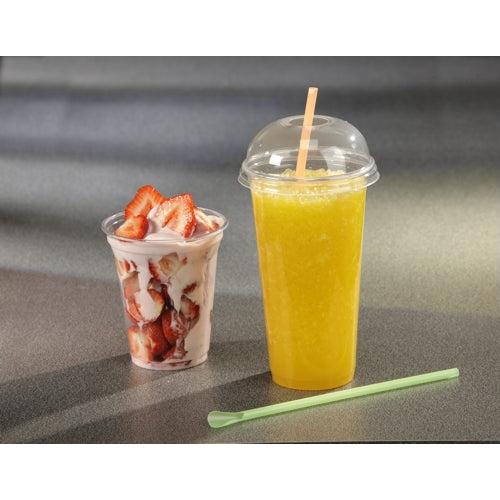 A clear cup with strawberry parfait, sliced strawberries, and yogurt stands next to a tall Starpak smoothie cup made of crystal-clear PET with a Starpak 50 dome lid "Hurricane" (round, Ø 9.5 cm – 4.5 cm); on the gray surface lies a green stir stick.