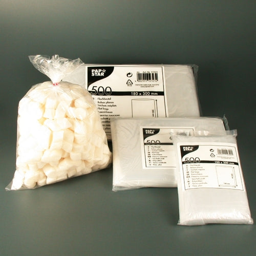 A set of products from PAPSTAR GmbH, consisting of a bag of white sugar cubes and three packs of PAPSTAR 500 flat bags LDPE transparent in various sizes, presented on a simple gray background as transparent packaging solutions.