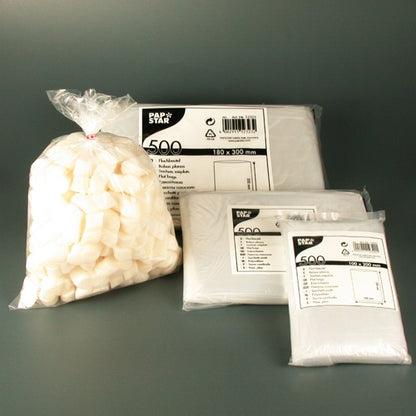 A transparent plastic bag with white sugar cubes lies next to three stacks of Starpak 500 flat bags, transparent LDPE, each in branded packaging with product information and the number 500, highlighting this high-quality packaging solution.