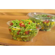 A Starpak 50 lid for salad bowls, R-PET round Ø 18 cm, clear, covers a salad of leafy greens, cherry tomatoes, and yellow peppers on a brown surface. In the background, another Starpak salad container made of clear R-PET can be seen.