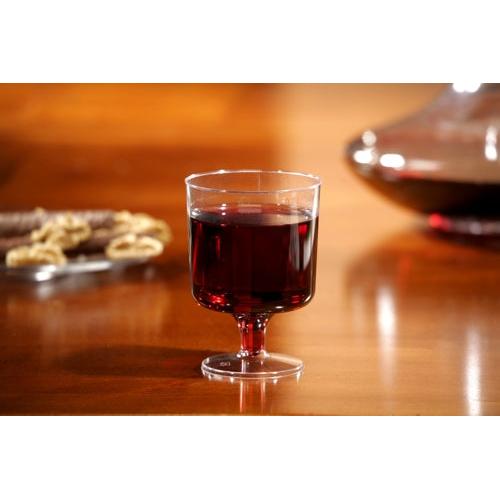 A Starpak 10 stem glasses for red wine, PS 0.2 l crystal-clear wine glass is filled and stands on a wooden table; Blurred snacks and a carafe can be seen in the background.
