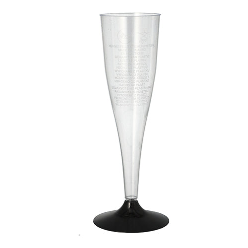 A clear Starpak champagne stem glass (0.1 l, Ø 5 cm, 17.5 cm) made of polystyrene with a black base stands upright on a white surface. The package contains six elegant glasses with subtle vertical text on the rim.