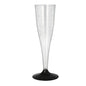 A clear Starpak champagne stem glass (0.1 l, Ø 5 cm, 17.5 cm) made of polystyrene with a black base stands upright on a white surface. The package contains six elegant glasses with subtle vertical text on the rim.