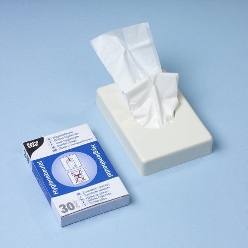 A white tissue dispenser stands next to a Starpak 30 sanitary bag dispenser box (28.5 x 8 x 7 cm, white), which contains 30 sanitary bags with instructional images on a light blue surface.