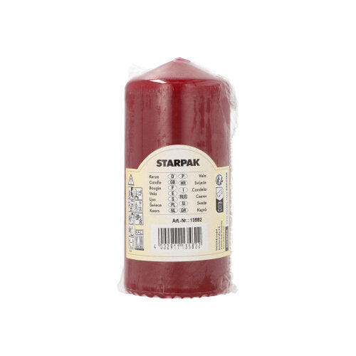 A red Starpak pillar candle (Ø 60 mm, 130 mm) with extra long burning time is packaged in transparent plastic and provided with a beige label with brand name, product details, barcode, and safety symbols for long use.
