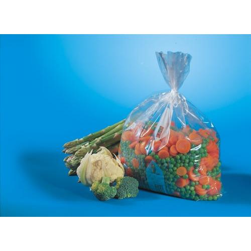 A transparent Starpak 100 freezer bag (1 l, 24 cm x 16 cm) contains frozen mixed vegetables and lies next to fresh asparagus, cauliflower, and broccoli florets on a blue background.