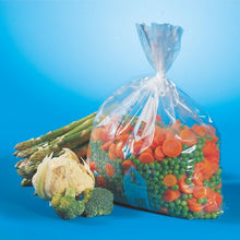A transparent Starpak 60 freezer bag (LLDPE, 4 l, 40 x 25 cm), filled with frozen mixed vegetables, lies on a blue surface next to fresh asparagus, cauliflower, and broccoli.