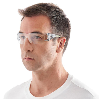 A man with short brown hair wears a 3M™ SecureFit™ Safety Glasses 400 from 3M Deutschland GmbH and a white crew-neck T-shirt, looking straight ahead against a white background.