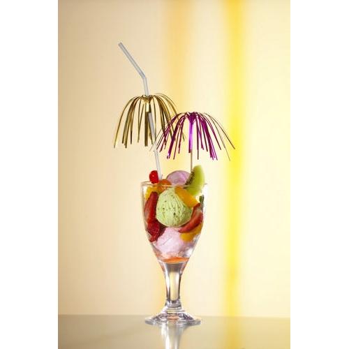 A glass with colorful ice cream, fruit slices, and cherries is stylishly presented with two decoration picks PAPSTAR 100 from PAPSTAR GmbH, umbrellas, and straws, in front of a light yellow background with a vertical yellow stripe.