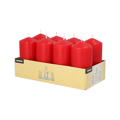 A box contains eight upright red Starpak pillar candles (Ø 50 mm, 100 mm) in two rows of four each. The label shows product information, the Starpak brand, and highlights the high-quality wax for a cozy atmosphere.
