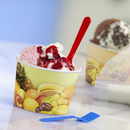 A pink-white ice cream cup with red sauce is served in a Starpak 50 ice cream cup round cardboard with fruit motifs. A red spoon is in the cup, a blue one lies beside it, and another Starpak cup can be seen in the background.