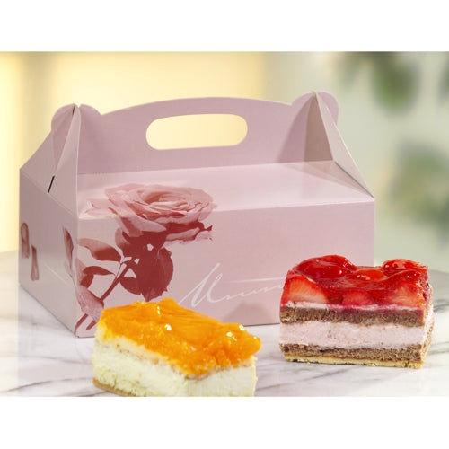 A PAPSTAR 15 pastry boxes, rectangular pink cardboard with a carrying handle from PAPSTAR GmbH stands on marble. In front are two slices of cake: one with orange topping, the other with red strawberry topping.