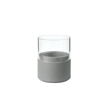 Der Kerzenhalter Glas Neat 70 x 61 mm von Duni GmbH zeichnet sich durch eine klare Glasplatte und einen hellgrauen Betonsockel mit glatten Oberflächen und klaren Linien aus, wodurch ein minimalistisches, modernes Wohnaccessoire entsteht.