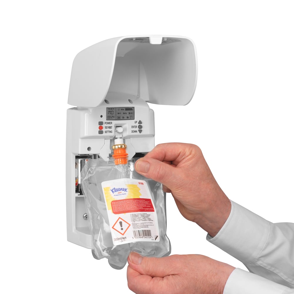A person inserts a Kleenex® Scent Joy refill pack (300 ml, transparent) from Kimberly-Clark GmbH into a white wall dispenser, ensuring long-lasting freshness with visible buttons and control lights.