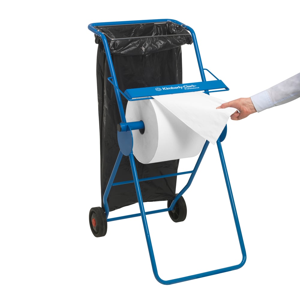 A mobile blue dispenser with two wheels holds a WypAll® L10 EXTRA wiping cloths large roll (white, 1500 sheets) from Kimberly-Clark GmbH; a black garbage bag is attached while a hand pulls a sheet from the large roll.