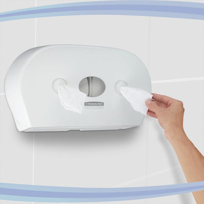 A hand pulls tissues from a Kimberly-Clark GmbH Aquarius™ toilet paper dispenser - central pull / white / Jumbo, equipped with two rolls and mounted on a tiled wall.