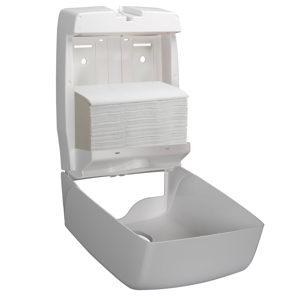 A white wall-mounted dispenser with an open front shows a stack of Scott® ESSENTIAL™ Hand Towels Interfold White Small from Kimberly-Clark GmbH (15 clips x 340 sheets) neatly inside.