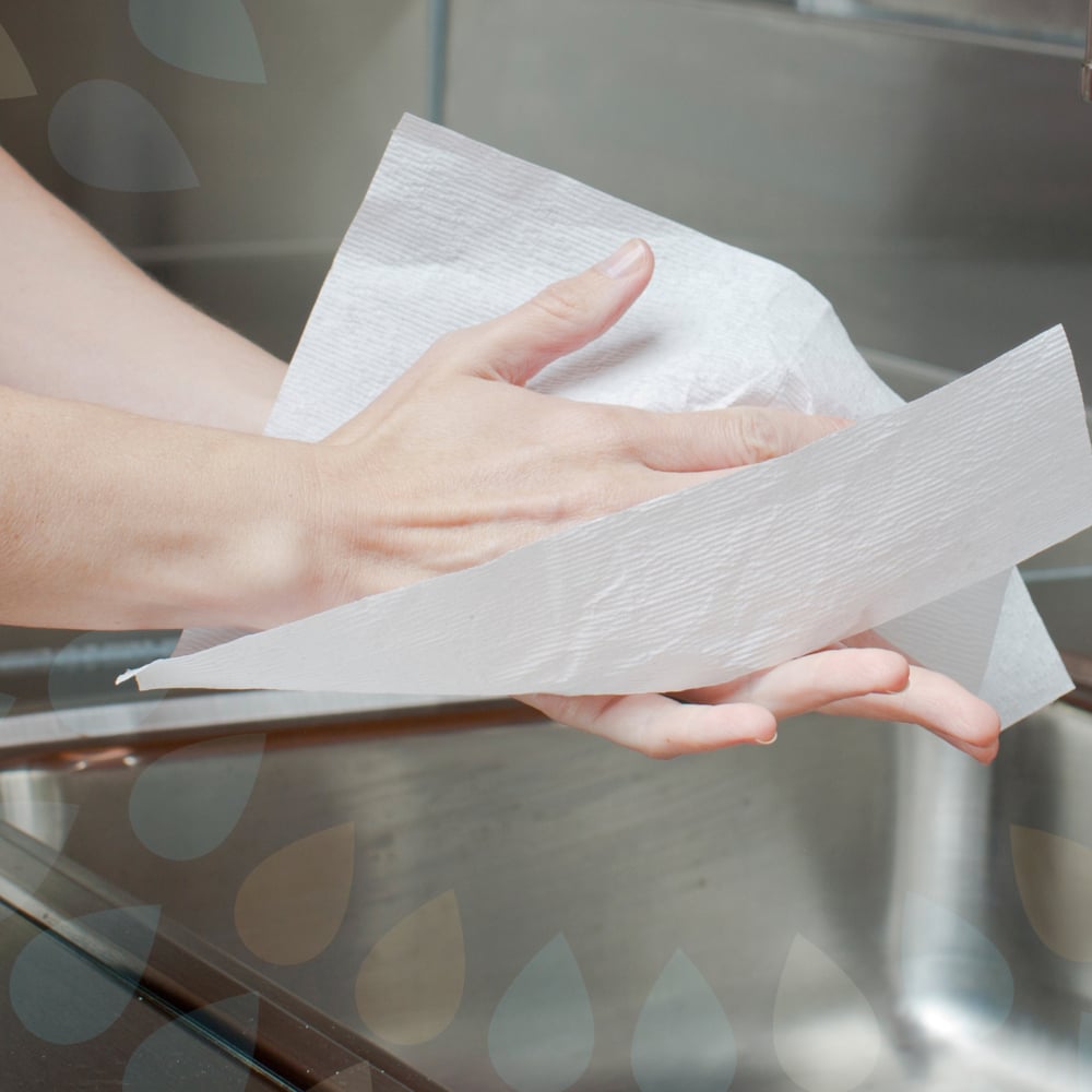 Someone is drying their clean hands with Kleenex® Ultra™ Hand Towels—Interfold, White, Medium (70 count, Kimberly-Clark GmbH) over a sink; part of the faucet is visible in the background.