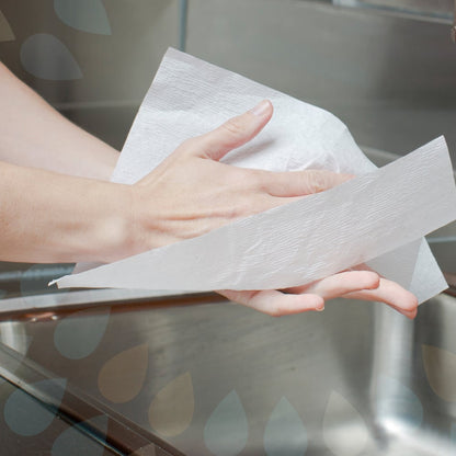 Someone is drying their clean hands with Kleenex® Ultra™ Hand Towels—Interfold, White, Medium (70 count, Kimberly-Clark GmbH) over a sink; part of the faucet is visible in the background.