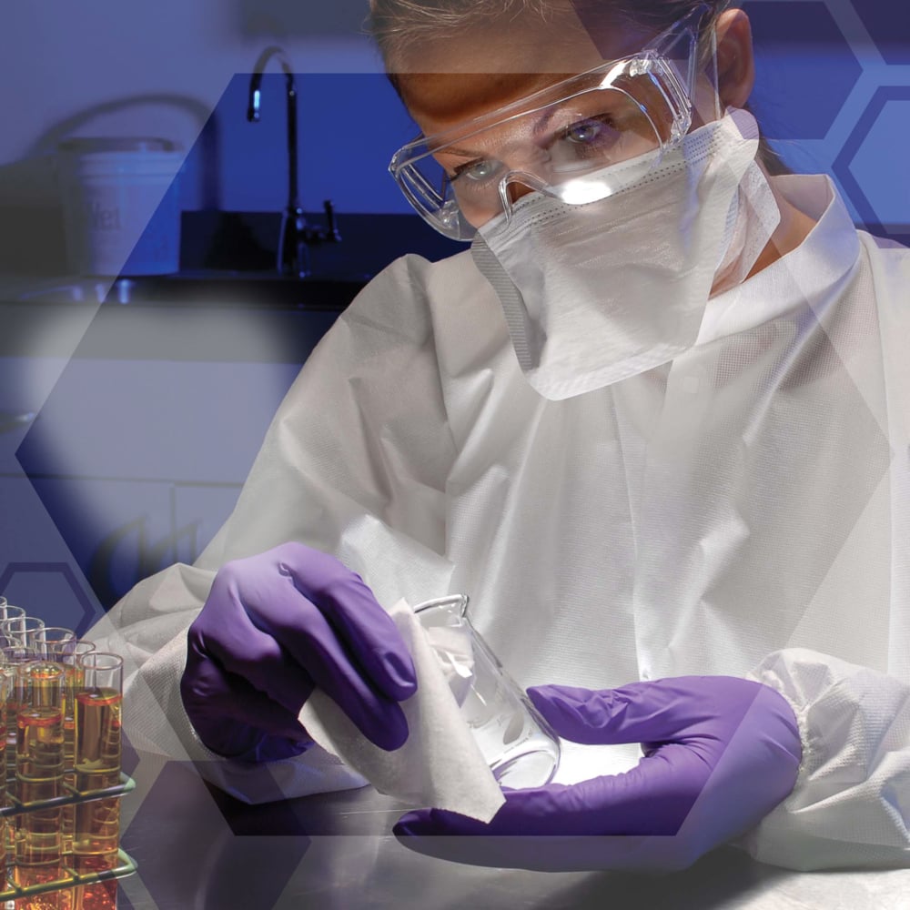 A scientist with safety goggles, mask, and purple gloves wipes a laboratory flask with Kimtech® Science precision wipes from Kimberly-Clark GmbH. Test tubes and hexagonal graphics appear on the table. Product: 30 cartons x 286 sheets per carton.