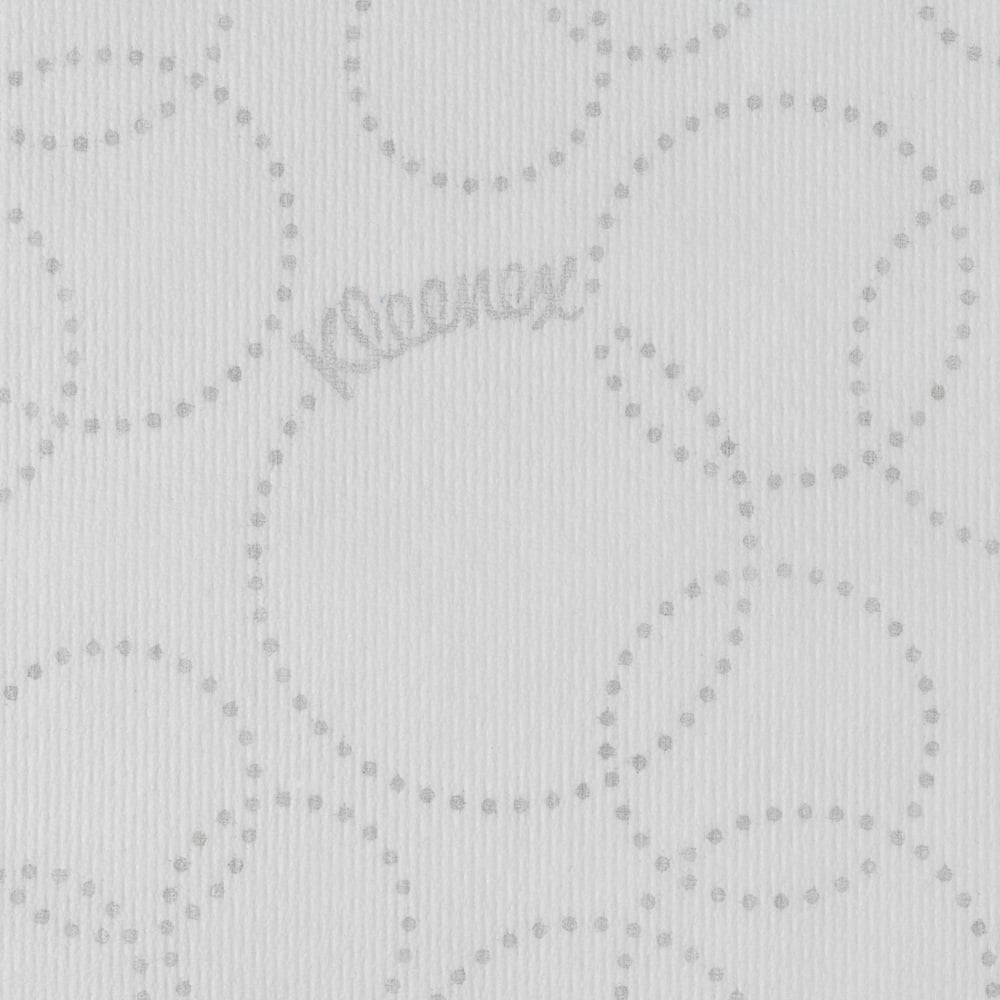 The close-up of a white Kleenex® Ultra™ Hand Towels MultiFold paper towel by Kimberly-Clark GmbH shows a light gray, dotted, circular pattern, subtle "Kleenex" branding between the dots, and a slightly ribbed texture.