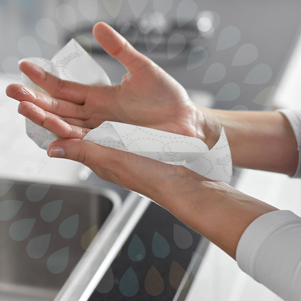 A person wipes their hands with white Kleenex® Roll Towels E-roll Slimroll™ paper towels (1-ply, 6x135m) from Kimberly-Clark GmbH over a sink, with water droplets overlaid on the image.