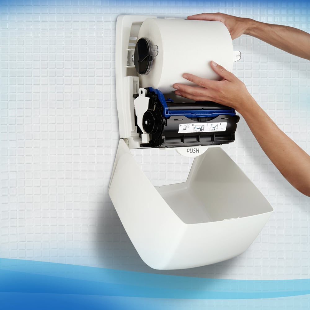 A person installs a Scott® Control™ towel - roll / white from Kimberly-Clark GmbH in a wall dispenser on a tiled wall for hygienic hand drying.