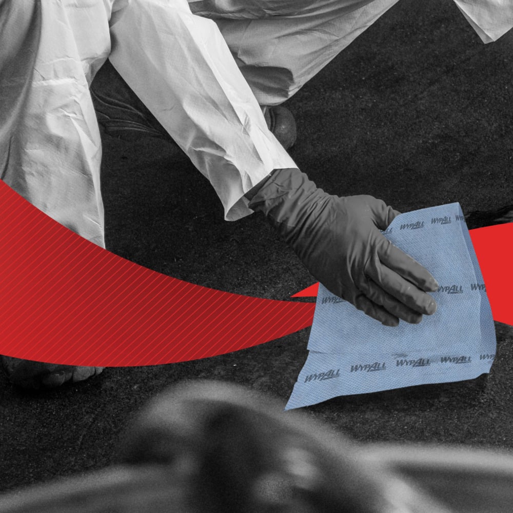 A person in protective clothing and gloves wipes a dark surface with WypAll® ForceMax wipes (blue, 33.50 x 34.50 cm, 480 wipes/dispenser box) from Kimberly-Clark GmbH. A red graphic element runs diagonally across the image.