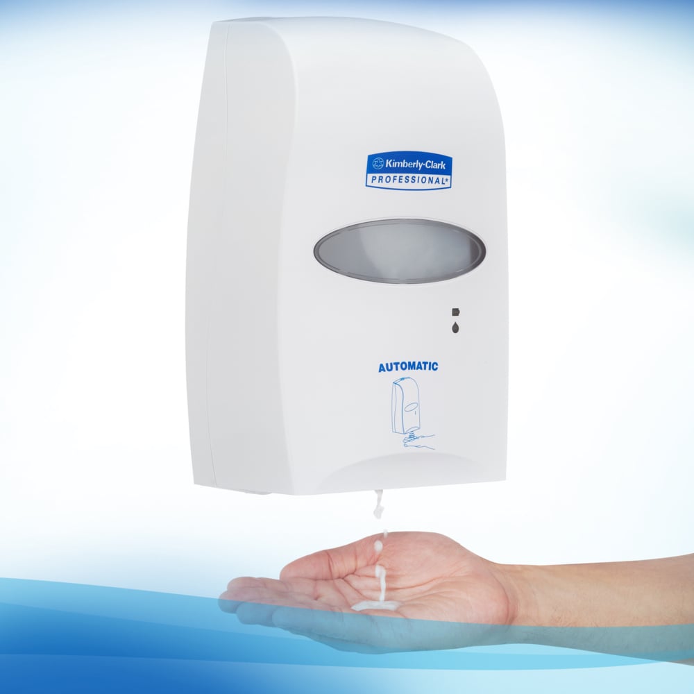 Ein wandmontierter Automat mit der Aufschrift "Kimberly-Clark GmbH" spendet Scott® CONTROL alkoholbasierten Handdesinfektionsschaum (1,2L Kassette) für optimale Handhygiene. Die transparente Einheit ist auf weißem Hintergrund mit blauen Akzenten abgebildet.