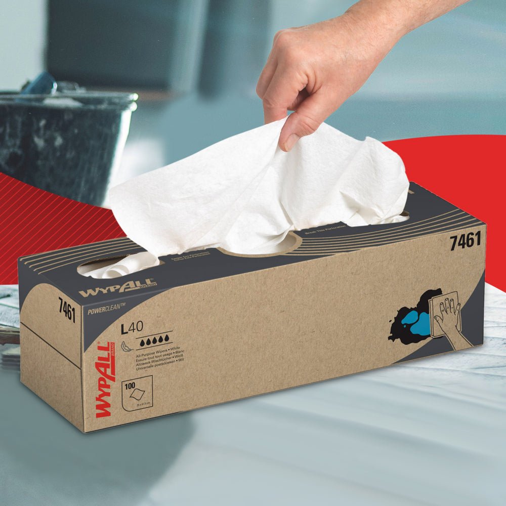 A hand pulls a white sheet from a brown WypAll® L40 PowerClean pull box from Kimberly-Clark GmbH. Ideal for industrial cleaning, the box displays product information and an image of high-performance cleaning wipes in use.