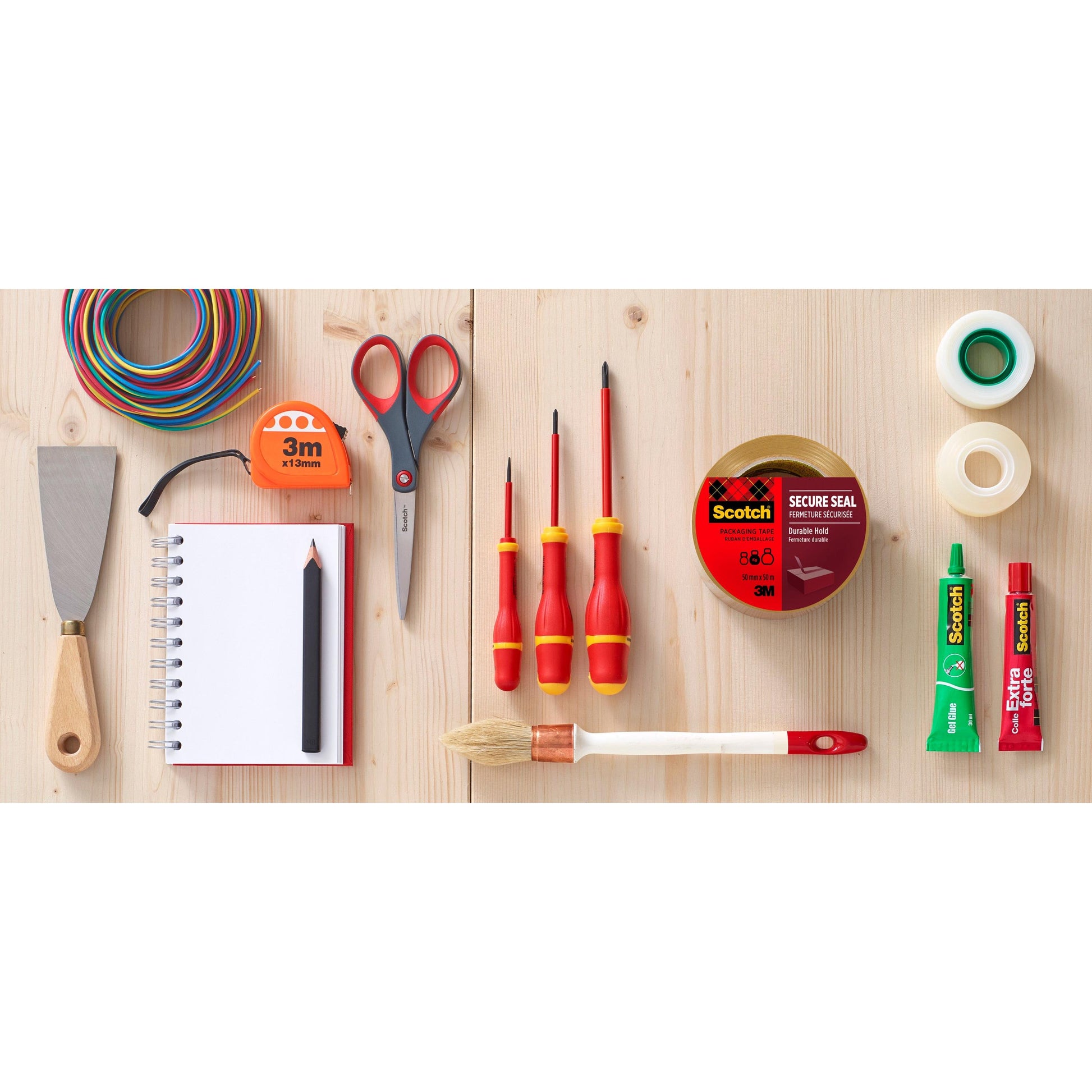 Verschiedene Werkzeuge und Verbrauchsmaterialien, darunter der 3M Deutschland GmbH Abroller mit Pistolengriff + Scotch® Verpackungsklebeband (50 mm x 66 m, Braun, 1 Spender + 2 Rollen/Packung), ausgestellt auf einer Holzfläche.