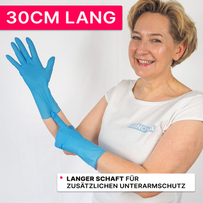 A person in a white shirt and blue nitrile gloves from ARNOWA GmbH smiles and points to the 30 cm long cuff. On a pink banner it says "30CM LONG" indicating that the ARNOMED NITRIL BLUE XTRA LONG gloves offer additional protection for the forearm.