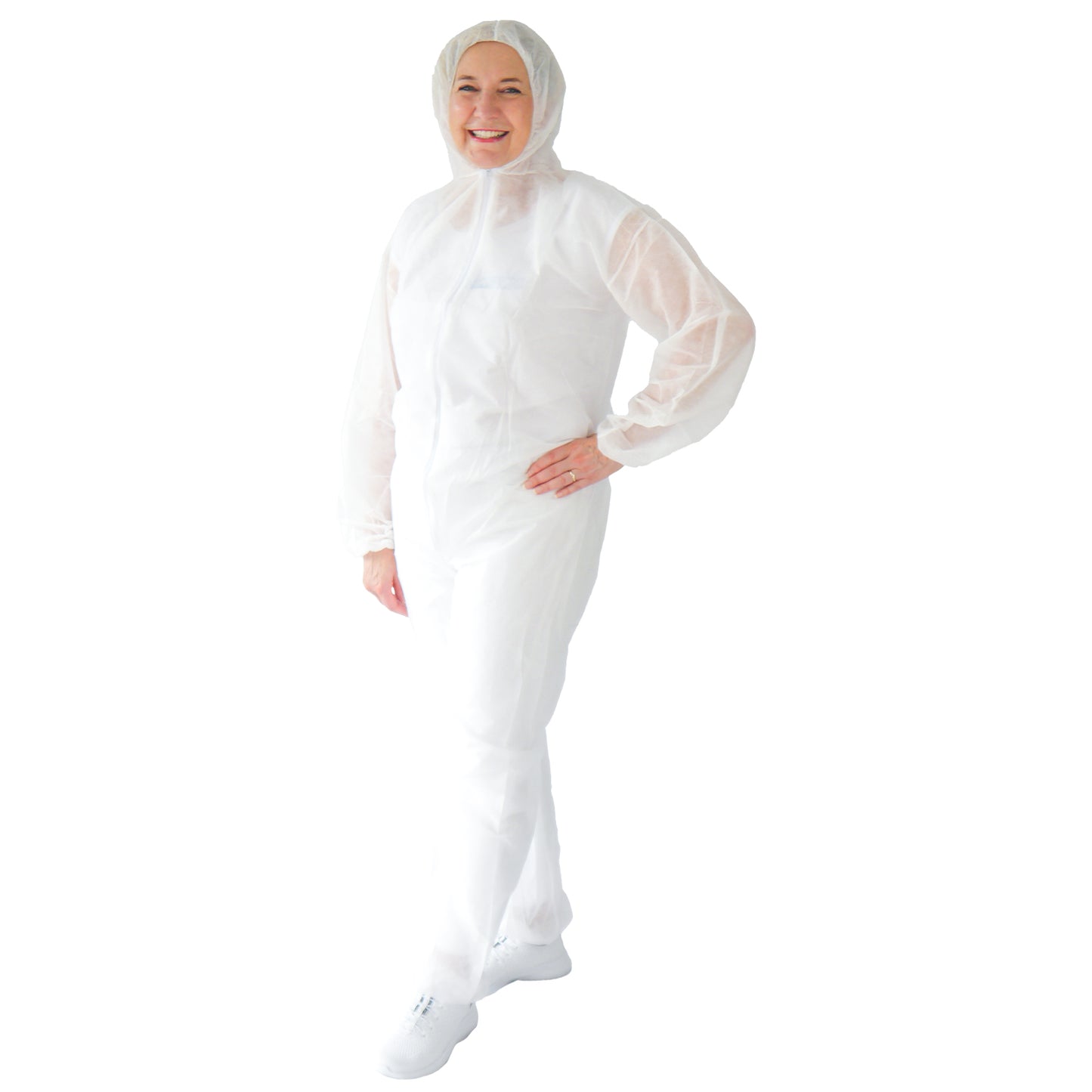A person is standing smiling in an ARNOMED COVER PP-OVERALL WHITE disposable overall with a hood made of PP fleece in white by ARNOWA GmbH, paired with white shoes. The background is solid white.