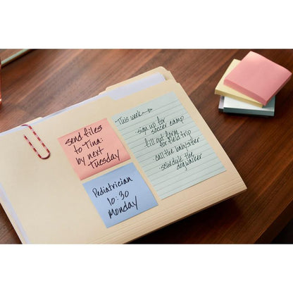 On a wooden desk lies a folder with blue, pink, and yellow Post-it® Recycling Z-Notes (76 mm x 76 mm, 100 sheets/block, 100% PEFC) by 3M Deutschland GmbH with handwritten reminders. Colorful, unused notes are stacked next to it.