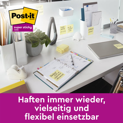 Ein aufgeräumter weißer Schreibtisch mit Laptop, Notebook und Pflanze, an dem 3M Deutschland GmbH Post-it® Super Sticky Notes, Gelb (76 mm x 76 mm) befestigt sind. Deutscher Text: "Haften immer wieder, vielseitig und flexibel einsetzbar.