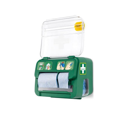 The green, wall-mounted Cederroth soft foam bandage 2-in-1 dispenser from Orkla Wound Care AB holds six bandages, has a transparent lid with a cross symbol, blue paper rolls, a pictorial guide, and a yellow tool for emergency wound care on the top.