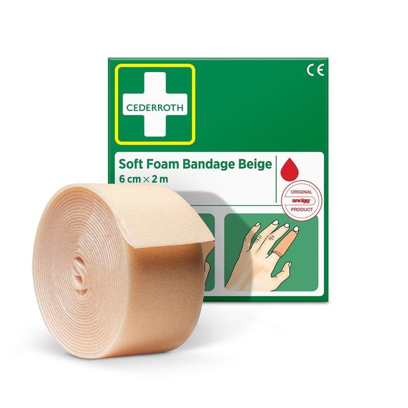 A roll of beige Cederroth soft foam bandage (6 cm x 2 m) from Orkla Wound Care AB is shown in front of its green-white packaging with illustrated instructions and a red drop symbol.