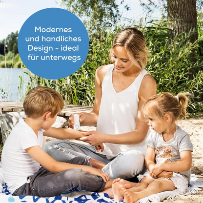 A woman sits with two children on a blanket by the water and demonstrates the Beurer GmbH discontinued item: insect bite healer BR 60 for treating insect bites. A blue circle emphasizes its modern, portable design with German text.