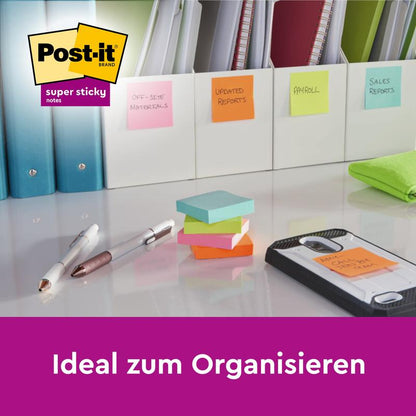 Several stacks of Post-it® Super Sticky Notes in large format, lined (101 mm x 101 mm, 45 sheets/block, 100% PEFC) from 3M Deutschland GmbH as well as writing utensils and folders are neatly arranged on a table. "Ideal for organizing."