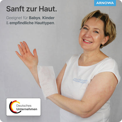A woman in a white shirt smiles while holding an ARNOMED disposable wash glove Spunlace with PE, water-repellent (bag, 50 pieces) by ARNOWA GmbH over her arm. The German text highlights gentle care for babies, children, and sensitive skin.