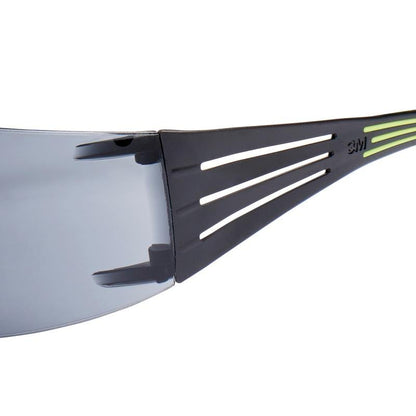 Close-up of the 3M™ SecureFit™ Safety Glasses 400 from 3M Deutschland GmbH, showing the black frame with thin horizontal cutouts, a small green stripe, and a clear lens.