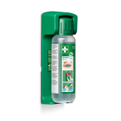 The Orkla Wound Care AB wall mount (for eye wash 500 ml) contains a glow-in-the-dark instruction sign and securely holds a clear eye wash bottle with usage instructions and diagrams. The package contains 1 piece.